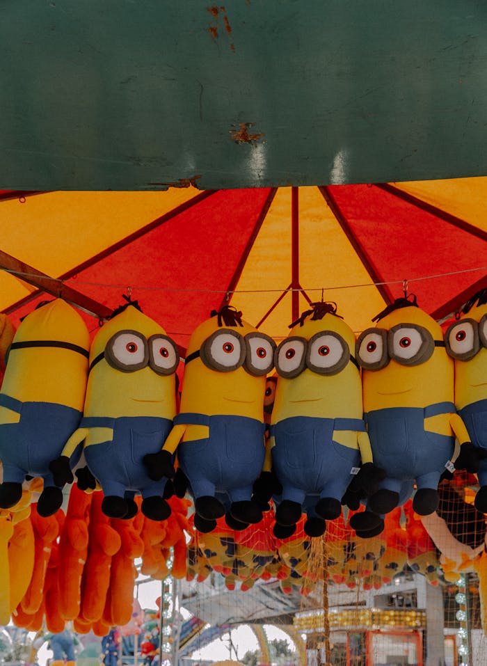 A vibrant carnival display featuring hanging Minion soft toys under a colorful canopy.